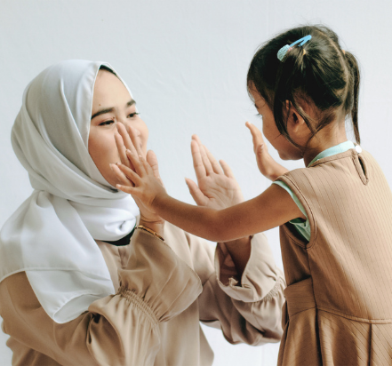 woman with hijab touching hands with daughter